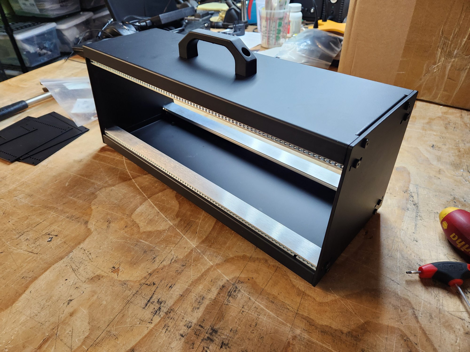 A black prototype case with a carry handle on top and an open front showing two rows of mounting rails
